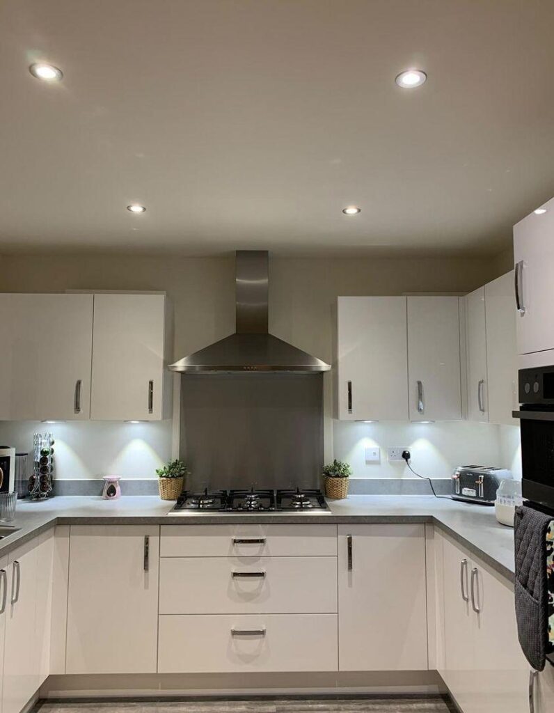 Modern kitchen with white cabinets, stainless steel stove, and range hood. Actions include equipped plants and under-cabinet lighting. Context features a tidy countertop with appliances and built-in lights.